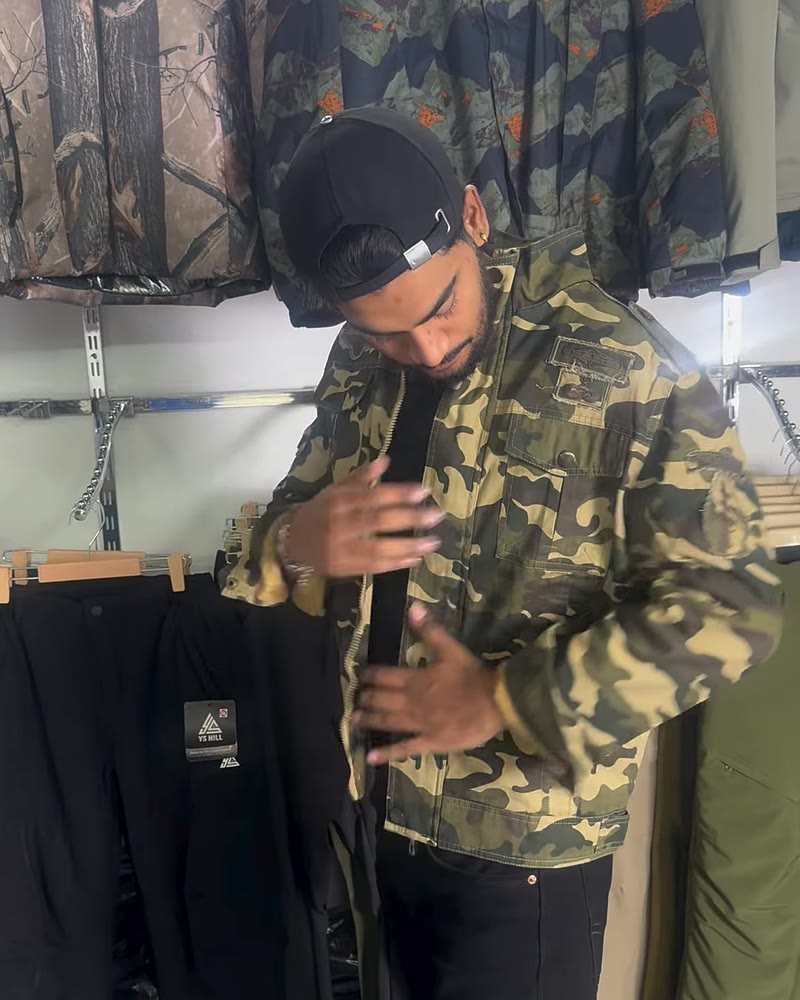 Man buttoning a woodland camo cotton jacket in the YS Hill store