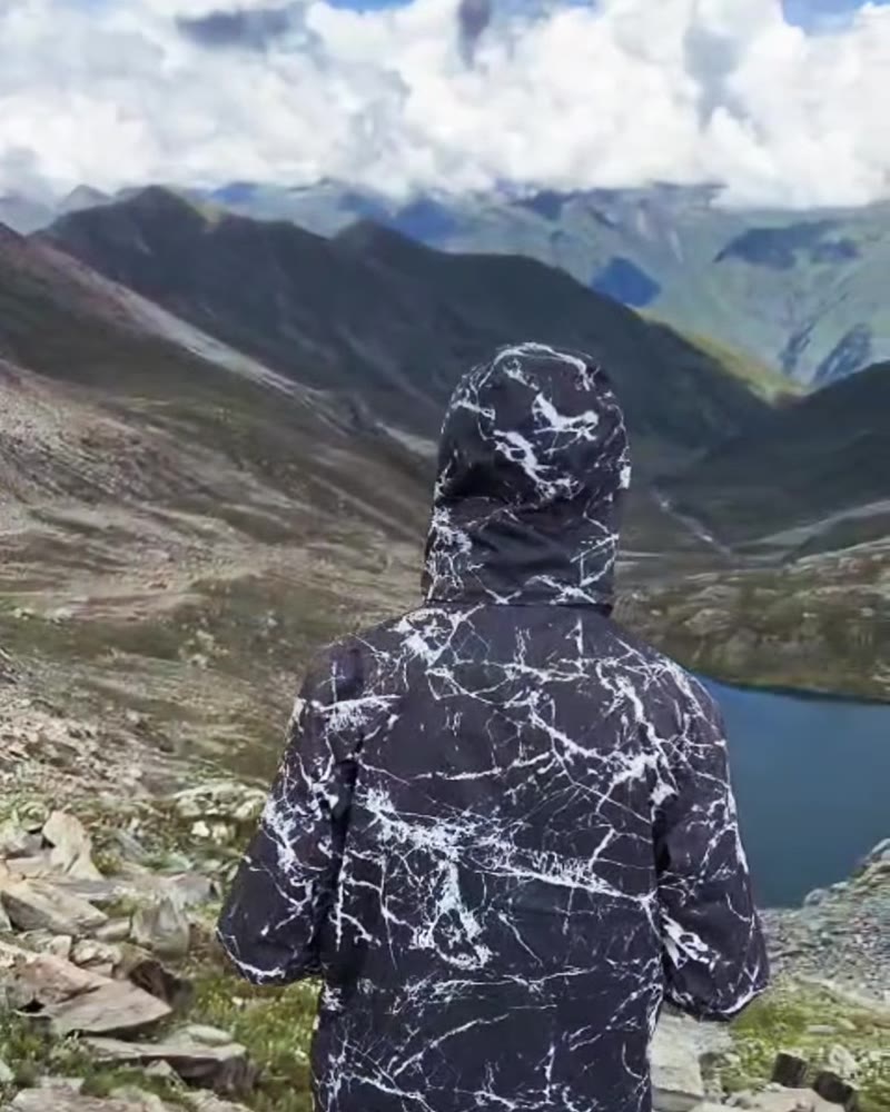 Hiker from behind in the hooded marble-print windcheater, looking at the lake