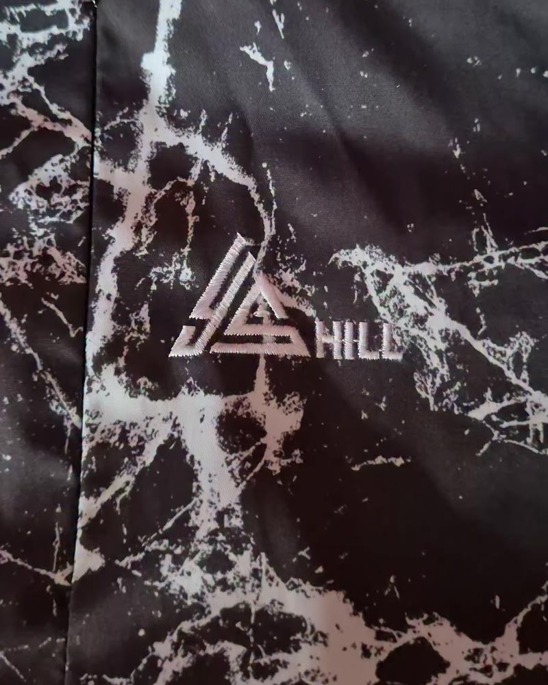 Close-up of the YS Hill logo printed on the marble-print shell