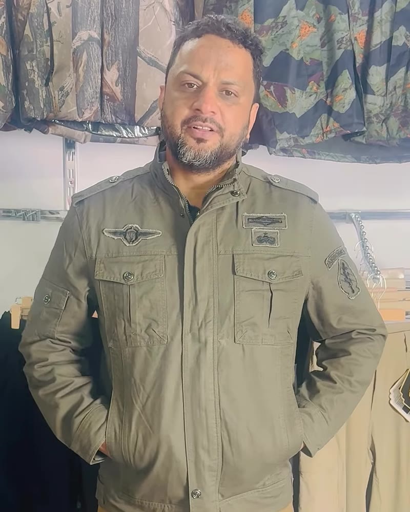Man in an olive cotton field jacket with chest pockets and badges