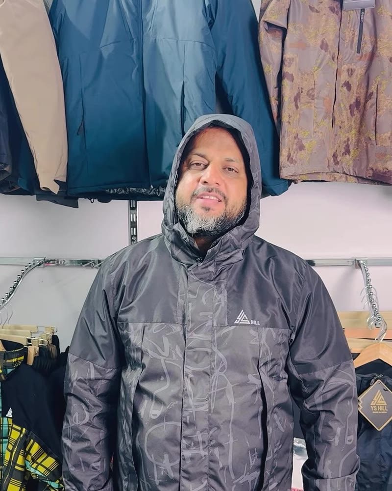 Man wearing a dark printed hooded shell jacket with the hood up