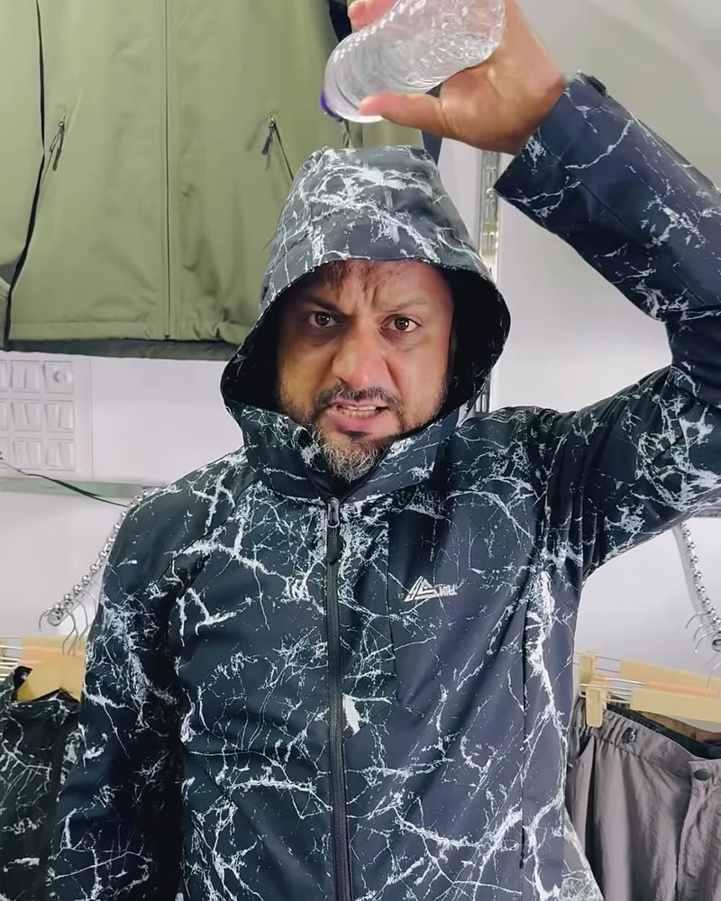 Water poured from a bottle over the hood of the windcheater